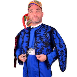 May include: A man wearing a blue and black embroidered jacket with a colorful patterned hat. The jacket has a high collar and long sleeves. The hat is a traditional style with a pointed top.