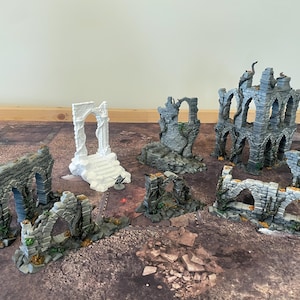Peut inclure: Un ensemble de six ruines miniatures imprimées en 3D de couleur grise et blanche pour jeux de table. Les ruines sont en pierre et ont un aspect vieilli. Elles sont parfaites pour ajouter une touche de réalisme à votre jeu.