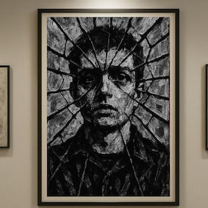 May include: A monochrome portrait print of a person's face, featuring a shattered glass effect. The artwork is framed in a black frame and displayed on a neutral wall. The art piece is a striking, modern piece.
