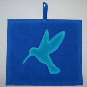 May include: A blue suede wall hanging with a turquoise blue hummingbird silhouette.