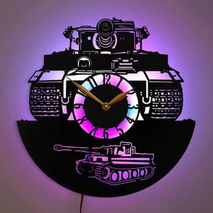 May include: A black vinyl record clock featuring a silhouette of a tank. The clock face is circular with a gold clock hand and a rainbow coloured background. The tank is a German Tiger tank with the number 131 on the side.