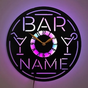 May include: A black vinyl record clock with a gold clock hand and a colorful LED light display. The clock face features the text "BAR YOUR NAME" with martini glass icons on either side.