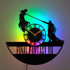 May include: A circular wall clock featuring a black silhouette of two characters engaged in a sword fight from Final Fantasy VII. The clock face has gold hands and the text FINAL FANTASY VII at the bottom, illuminated by a vibrant rainbow LED light.