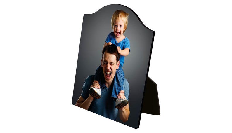 May include: A black wooden photo frame with a curved top and a stand. The frame displays a photograph of a man and a child. The man is wearing a blue shirt and the child is sitting on his shoulders, both with their mouths open.