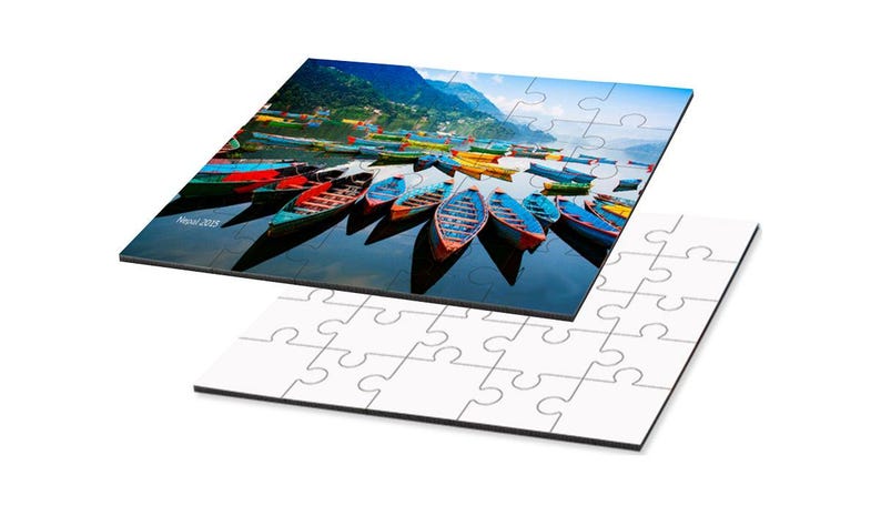 May include: A jigsaw puzzle featuring a scenic image of colorful boats on a lake with mountains in the background. The puzzle is partially assembled, with the completed image on top and the unassembled pieces below.