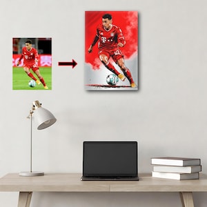 Op de afbeelding: Een canvas print met een voetballer in een rood tenue, die een voetbal dribbelt. Het kunstwerk heeft een gestileerd ontwerp met rode en grijze achtergrondelementen. De speler draagt nummer 42.