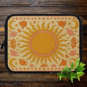 Peut inclure: Une housse d'ordinateur portable avec un motif rétro de soleil et de lune. Le soleil est jaune et orange avec des rayons roses. La lune est blanche avec une forme de croissant. Il y a de petits oiseaux et des étoiles éparpillés autour du soleil et de la lune.