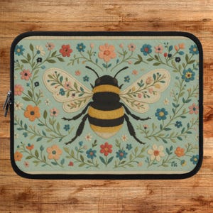 Puede incluir: Un patrón floral azul y verde con una abeja amarilla y negra en el centro. La abeja tiene alas florales y está rodeada de flores y hojas.