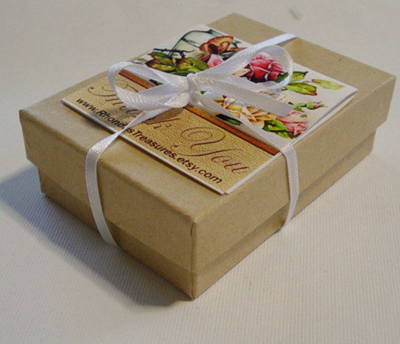 May include: A small, brown cardboard box with a white ribbon tied around it. The box has a label that says "Thank You" and "www.RhondasTreasures.etsy.com".