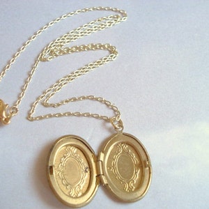 May include: A gold chain necklace with an oval locket pendant. The locket is open, revealing two empty compartments.