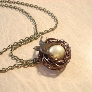 May include: A bronze necklace with a bird and pearl in a wire nest pendant.