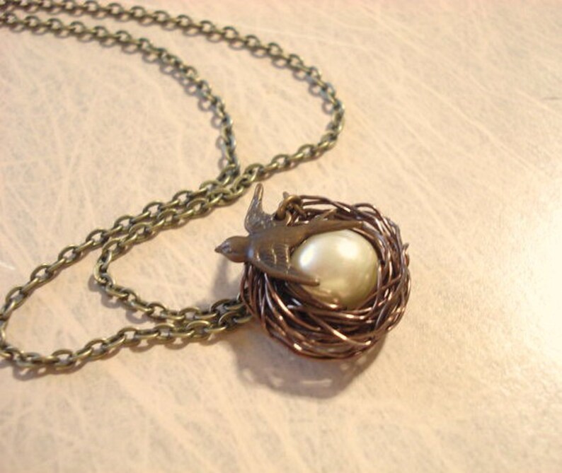 May include: A bronze necklace with a bird and pearl in a wire nest pendant.