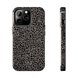 May include: A speckled phone case in shades of gray and black. The case has a textured pattern and a camera cutout. The side view shows the case's thickness and button placement. The brand name is visible at the bottom.