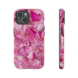 May include: A pink phone case with a mosaic design. The case features a pattern of irregular, angular shapes in varying shades of pink, with gold-colored accents between the pieces. The phone case is shown from the front and side.