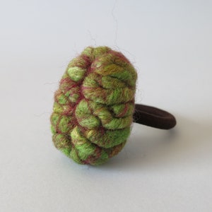 May include: Green and red felted wool hair scrunchie with a brown elastic band.