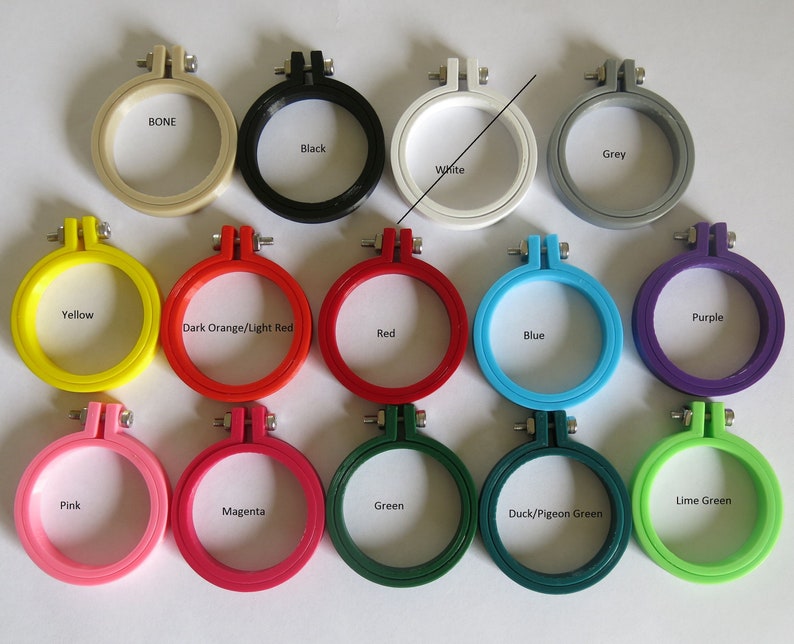 May include: A set of 12 embroidery hoops in various colours, including bone, black, grey, white, yellow, dark orange/light red, red, blue, pink, magenta, green, duck/pigeon green, and lime green.