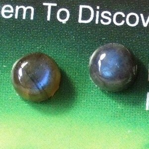 May include: Two round, dark blue labradorite gemstones with iridescent flashes of colour. The gemstones are labelled "Labradorite Newfoundland".