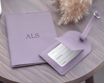 May include: A set of two lavender leather travel accessories. The larger piece is a passport holder with the monogram "ALS" embossed on the front. The smaller piece is a luggage tag with a flap that opens to reveal a space for writing contact information.