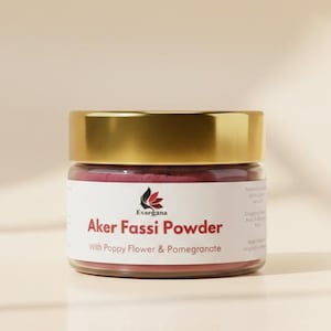 Könnte beinhalten: Ein kleines Glas mit goldenem Deckel enthält Aker Fassi-Pulver. Auf dem Etikett steht "Aker Fassi Powder with Poppy Flower & Pomegranate". Das Pulver hat eine tiefrot-rosa Farbe. Das Glas steht vor einem neutralen Hintergrund.
