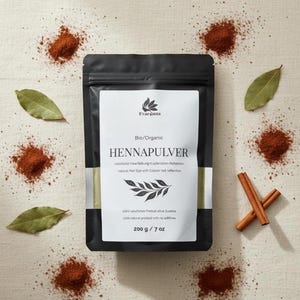 May include: A black pouch of Henna powder with a white label, surrounded by cinnamon sticks, bay leaves, and scattered red-brown powder. The label reads "Bio/Organic HENNAPULVER natural Hair Dye with Copper red reflection". The pouch contains 200 g / 7 oz.