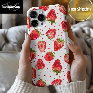 May include: White iPhone case with a red and white strawberry pattern. The case has a camera lens cutout and a white background with red dots.