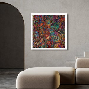 Puede incluir: Impresión de arte abstracto con un patrón colorido y arremolinado de rojo, naranja, amarillo, verde, azul y morado. La impresión está enmarcada en un marco blanco y cuelga de una pared gris.