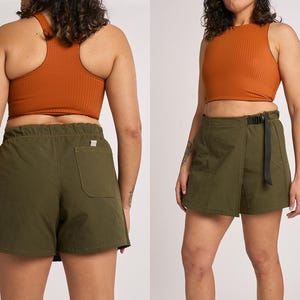 May include: A rust-colored ribbed racerback crop top paired with olive green wrap shorts. The shorts feature an elastic waistband, a black adjustable webbing belt with a buckle, and a single patch pocket on the back with a small white label.