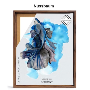 May include: A framed canvas print of a blue betta fish with a long, flowing tail. The fish is swimming in a blue and white watercolor background. The frame is made of wood and has a brown finish. The text "MADE IN GERMANY" is printed on the canvas.