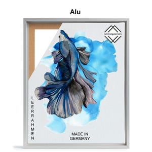 May include: A blue and silver fish with flowing fins is painted on a white canvas with blue watercolor accents. The canvas is framed in a silver frame with the words "LEERAHMEN" and "MADE IN GERMANY" printed on the side. The text "rahmenggalerie24" is printed in the top right corner of the canvas.
