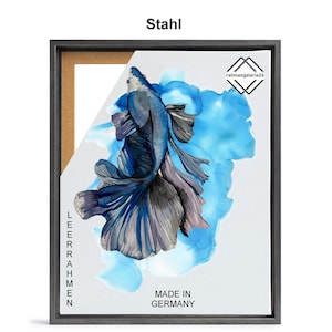 May include: A framed print of a blue betta fish with a long, flowing tail, swimming in a blue and white watercolor background. The frame is made of wood and has a black finish. The print is titled "Stahl" and includes the text "Made in Germany".