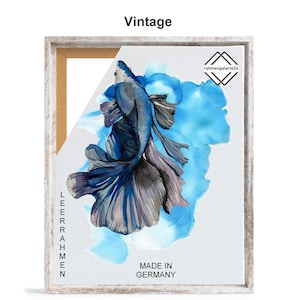 May include: A framed print of a blue and silver betta fish with a blue and white watercolor background. The print is titled "Vintage" and has the text "Made in Germany" at the bottom. The frame is a light wood color.