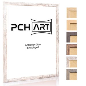 Peut inclure: Cadre photo en bois blanc avec une finition vieillie. Le cadre a un bord biseauté et un verre anti-reflet clair. Le cadre est présenté sur un fond blanc avec le texte "PCHART" et "Antireflex-Glas Entspiegelt" visible dans le cadre. Le cadre est présenté dans une variété d'autres couleurs.