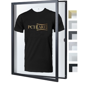 Könnte beinhalten: Schwarzer Rahmen mit einem schwarzen T-Shirt darin. Das T-Shirt hat ein goldenes Logo mit der Aufschrift "PCH ART".