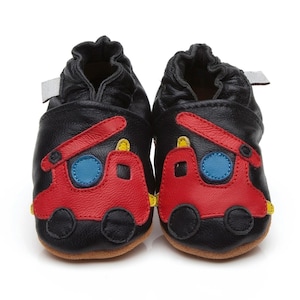 Könnte beinhalten: Schwarze Lederschuhe für Babys mit einem roten Feuerwehrauto-Design. Die Schuhe haben gelbe und blaue Akzente.