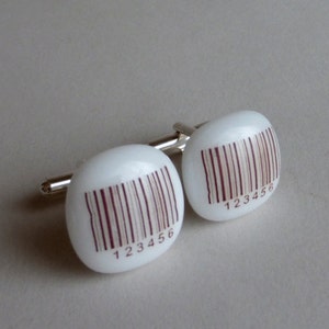 May include: A pair of white cufflinks with a brown barcode design and the numbers 123456 printed on each cufflink.
