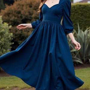 Puede incluir: Un vestido midi azul oscuro con escote de corazón y mangas largas. El vestido tiene un corpiño ajustado y una falda fluida.
