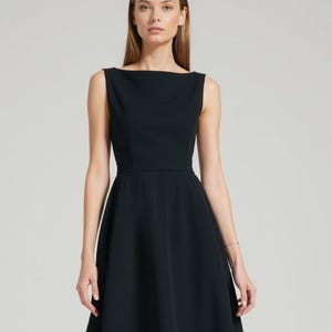K&ouml;nnte beinhalten: Ein schwarzes, &auml;rmelloses Kleid mit einem Boot Ausschnitt und einem ausgestellten Rock.