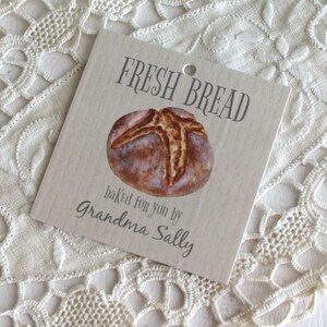 May include: A brown paper gift tag with the text "Fresh Bread" and a drawing of a loaf of bread. The text "baked for you by Grandma Sally" is printed below the bread.