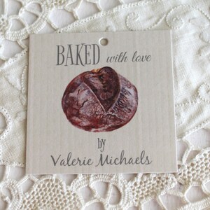 May include: A brown paper gift tag with the text "BAKED with love by Valerie Michaels" and a picture of a loaf of bread.