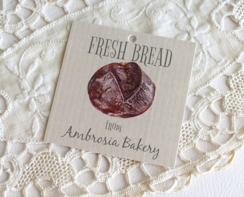 May include: A brown and white gift tag with the text "FRESH BREAD from Ambrosia Bakery". A drawing of a loaf of bread is in the center of the tag.