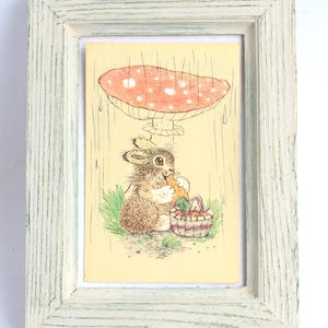 Carte postale de ferme lapin gris assis confortablement sous un champignon géant magnifiquement dans un cadre blanc rustique, décoration murale de carte postale vintage