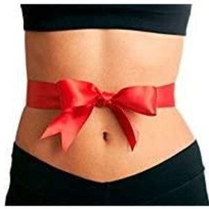 May include: A woman's torso with a red satin ribbon tied around her waist in a bow.