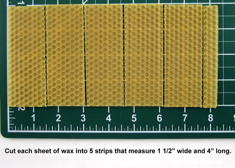 May include: Five strips of yellow beeswax foundation sheets, each measuring 1 1/2 inches wide and 4 inches long, are laid out on a green cutting mat with a ruler.