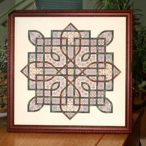 May include: A framed cross-stitch embroidery with a complex, intricate design featuring a Celtic knot pattern in shades of green, brown, red, and blue.