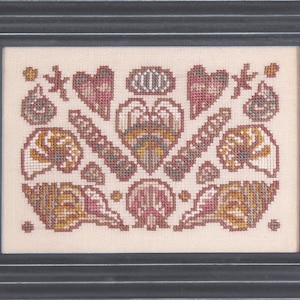 May include: A framed cross-stitch design featuring a variety of seashells in shades of brown, pink, and white. The shells are arranged in a symmetrical pattern, with a heart shape at the center.