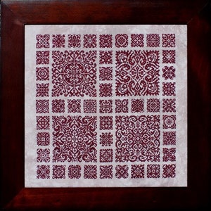 May include: A framed embroidery piece with a white background and a grid of 64 burgundy red squares, each containing a different intricate design.