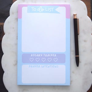 May include: A white ceramic mug with a black handle and the text "But First, Coffee" in a black, handwritten-style font. The mug is on a white surface.