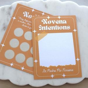 May include: Two rectangular paper cards with a mustard yellow background and white star accents. The top card features the text Novena Intentions and St. Padre Pio Novena with a large white central box. The bottom card displays nine light gray circles.