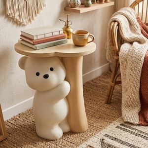 May include: A whimsical side table featuring a white bear base supporting a light wood-colored tabletop. The table holds books and a mug. The bear has black eyes and a friendly expression. The table is on a woven rug.