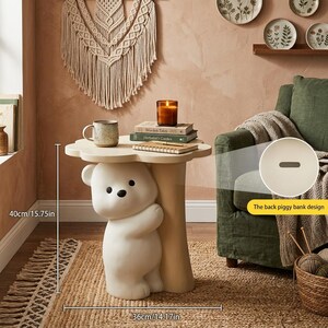 May include: A whimsical side table featuring a white bear hugging a beige tree trunk. The table has a cloud-shaped top and measures 15.75 inches high and 14.17 inches wide. The back has a piggy bank design.
